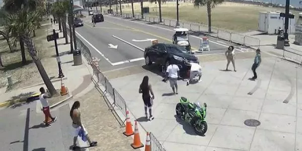 View from street camera of people and vehicles in an intersection.