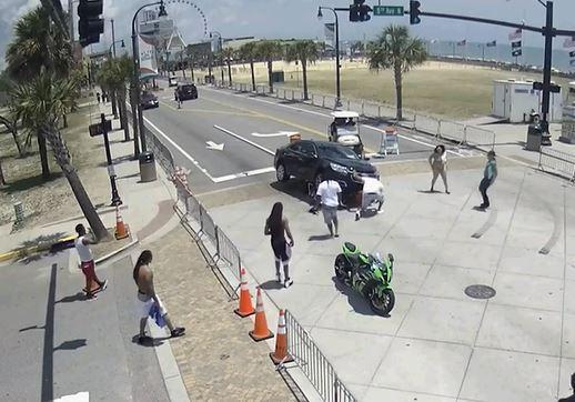View from street camera of people and vehicles in an intersection.